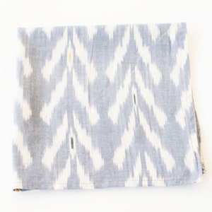 May include: A gray and white patterned fabric napkin with a subtle ikat design.