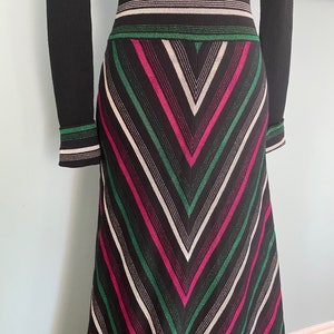 May include: A long black and white striped skirt with pink and green stripes. The skirt has a high waist and a flared silhouette.