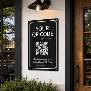Puede incluir: Un letrero rectangular negro con bordes blancos y esquinas redondeadas, que presenta el texto "YOUR QR CODE" en la parte superior, un código QR central y el texto "Customize your text and add your QR Code" en la parte inferior, montado en una pared.