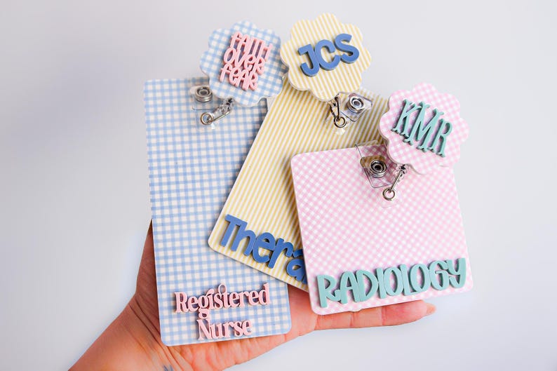 Puede incluir: Tres portatarjetas rectangulares con patrones de cuadros vichy en azul, amarillo y rosa. El azul incluye el texto "Faith Over Fear" y "Registered Nurse". El amarillo muestra "JCS" y "Therapy". El rosa presenta "KMR" y "RADIOLOGY".