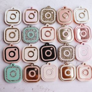 May include: Twenty assorted camera-shaped charms with various colors and finishes, including glitter, solid colors, and metallic finishes.