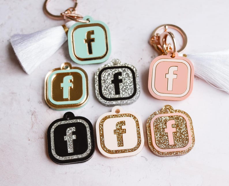 May include: Set of ten keychains featuring the Facebook logo in various colors and finishes. The keychains are made of metal and plastic and have a variety of designs, including glitter, solid colors, and silver.