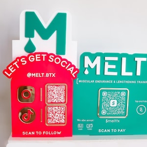 May include: Two-piece sign with the word "MELT" in white on a teal background. The sign includes a QR code and the text "MUSCULAR ENDURANCE & LENGTHENING TRAINING". A red sign with "LET'S GET SOCIAL" and social media icons is also present.