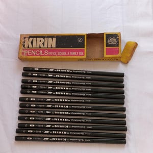 以下が含まれることがあります： 箱と鉛筆に「KIRIN」のブランド名が印刷された黒鉛筆の箱。鉛筆には「JAPAN Retouching KIRIN」と表示され、黒色の六角形の軸に白い文字が書かれています。