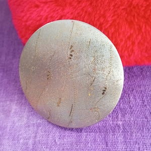 Può includere: Un ornamento rotondo in metallo argentato con una superficie testurizzata e un design di linee sottili e punti. L'ornamento ha un leggero bagliore.