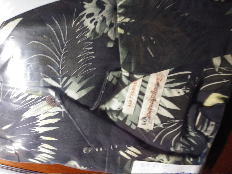 May include: A black button-down shirt with a tropical leaf print. The shirt has a label that reads "Original Fit" and "Tommy Bahama".