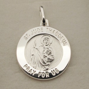 May include: Silver pendant with a round design featuring a depiction of Saint Jude Thaddeus. The pendant has the words "St. Jude Thaddeus" and "Pray for Us" inscribed around the image.