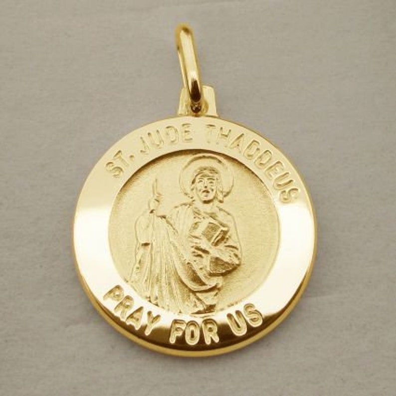 May include: Gold-toned pendant featuring a religious image of Saint Jude Thaddeus. The pendant is round and has the words "St. Jude Thaddeus" and "Pray for Us" inscribed around the image.