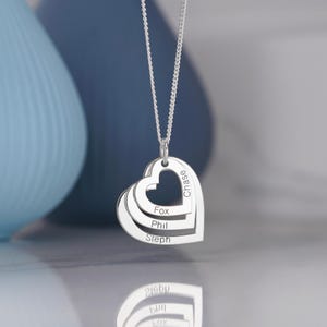 Puede incluir: Collar de plata con un colgante de coraz&oacute;n en capas grabado con los nombres Chase, Fox, Phil y Steph.
