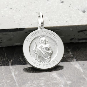 May include: Silver pendant featuring a round medal with a depiction of Saint Jude Thaddeus. The medal has the words "St. Jude Thaddeus" and "Pray for Us" inscribed around the image.