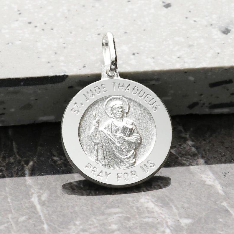 May include: Silver pendant featuring a round medal with a depiction of Saint Jude Thaddeus. The medal has the words "St. Jude Thaddeus" and "Pray for Us" inscribed around the image.