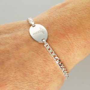 Puede incluir: Pulsera de alerta m&eacute;dica de plata con cadena de eslabones y una etiqueta redonda grabada con el s&iacute;mbolo del caduceo.