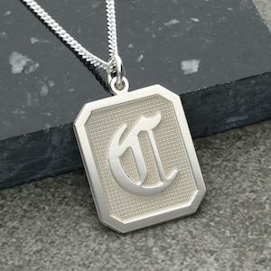May include: Silver necklace with a rectangular pendant featuring a large, stylized letter 'C' in a gothic font.