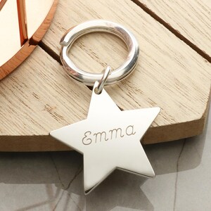 May include: Silver star-shaped keyring with a ring and the name "Emma" engraved on the front.