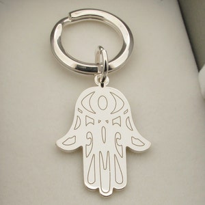 May include: Silver keychain with a hamsa hand charm. The hamsa hand is a popular symbol of protection and good luck.
