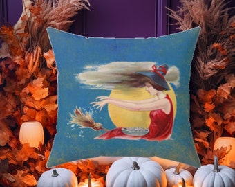 May include: Square throw pillow with a vintage illustration of a witch flying on a broom in front of a full moon. The witch wears a red dress and a black hat. The pillow is surrounded by white pumpkins and autumn foliage.