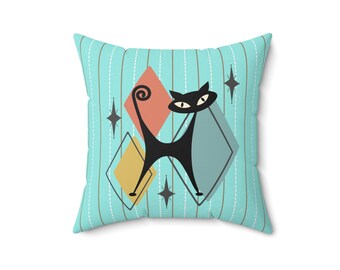 May include: A turquoise blue throw pillow with a black cat design. The cat is stylized with a long tail and large eyes. The background features a geometric pattern of diamonds in shades of blue, yellow, and red.