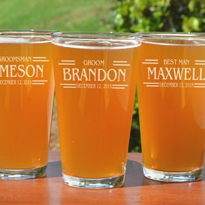 Puede incluir: Tres jarras de cerveza de vidrio transparente con texto personalizado. Las jarras est&aacute;n llenas de una bebida de color &aacute;mbar claro. El texto en las jarras dice "Groom, Best Man y Groomsman" con nombres y la fecha "December 12, 2015".