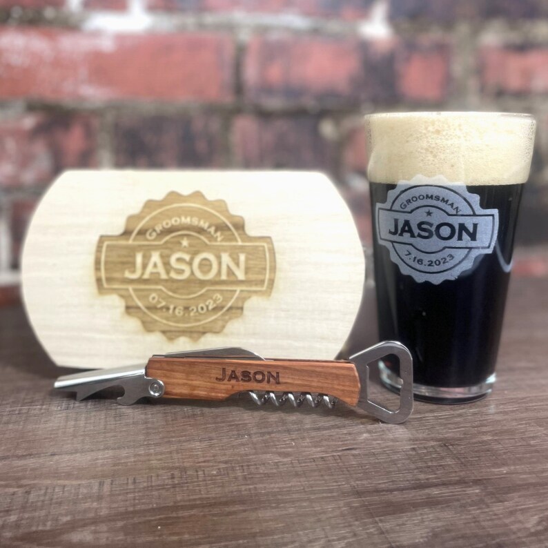 Puede incluir: Una caja de madera con un mensaje grabado personalizado para un padrino de boda llamado Jason. La caja incluye un abridor de botellas y una herramienta de sacacorchos con mango de madera. La fecha 07.16.2023 tambi&eacute;n est&aacute; grabada en la caja.