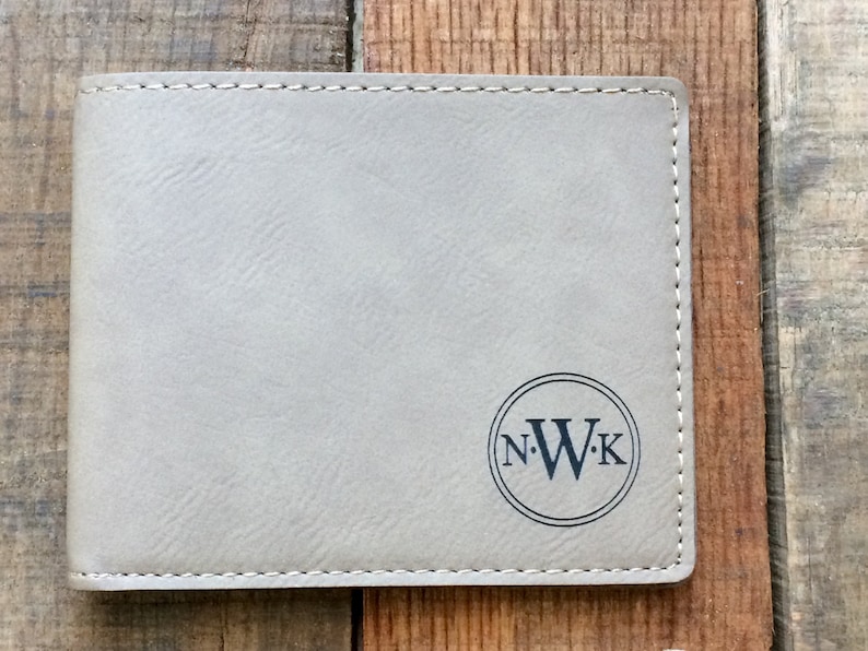 May include: A gray leather wallet with a stitched border and a circle monogrammed with the initials "N.W.K."