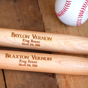 May include: Two wooden baseball bats with the names Brylon Vernon and Braxton Vernon engraved on them. The bats are engraved with the words "Ring Bearer" and "March 5th, 2016".