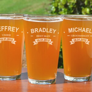 Puede incluir: Tres jarras de cerveza de vidrio transparente con texto personalizado y fechas. Las jarras est&aacute;n llenas de una bebida de color &aacute;mbar claro. El texto en las jarras dice "Jeffrey - Usher - 10.31.2015", "Bradley - Best Man - 10.31.2015" y "Michael - Groomsman - 10.31.2015".