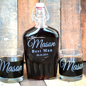 Op de afbeelding: Een gepersonaliseerde glazen likeurfles met een schroefdop en twee bijpassende glazen. De fles en de glazen zijn gegraveerd met de naam "Mason" en de tekst "Best Man 06.04.2016".