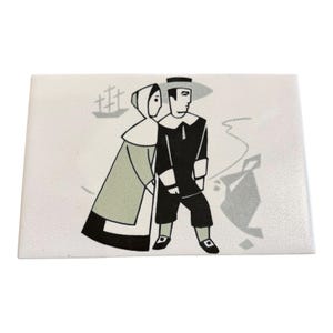May include: A rectangular white ceramic tile featuring a stylized black, gray, and sage green graphic illustration of two figures in historical attire. The design includes a ship silhouette in the background and a geometric shape to the right.
