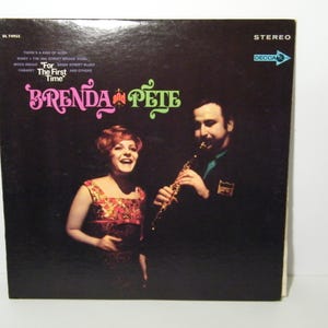May include: Vintage vinyl record album cover for "For The First Time" by Brenda and Pete. The cover features a woman in a floral dress and a man playing a clarinet. The album title is in pink and green script.