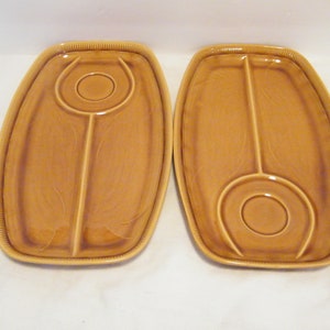 May include: Two brown ceramic serving trays with divided sections. Each tray has a small circular indentation in the center.