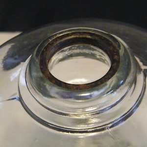 May include: Close-up of a clear glass lampshade with a rusty metal ring around the top opening.