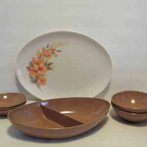 May include: A set of brown plastic serving dishes, including a large oval platter with a floral design, a divided serving bowl, and a set of three nesting bowls.