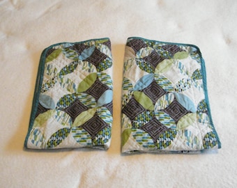 May include: Two quilted pillow covers with a geometric pattern of circles in shades of green, blue, and brown on a white background. The covers have a teal border.