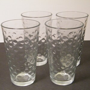 May include: Set of four clear glass drinking glasses with a textured, bubbled surface.