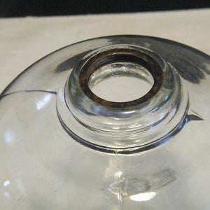 May include: A clear glass globe with a rusty metal rim around the opening. The globe is designed for a lamp or light fixture.