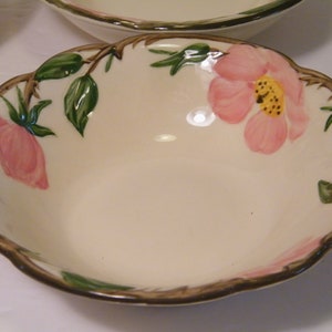 May include: A white ceramic bowl with a scalloped rim and a floral design featuring pink roses and green leaves.