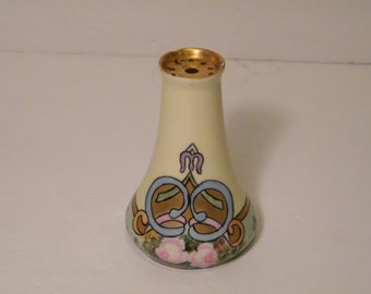 May include: A vintage ceramic salt shaker with a gold rim and a floral design. The shaker features a pale yellow background with blue, green, and pink accents. The design includes stylised floral motifs and a gold trim.