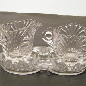 May include: A clear glass sugar and creamer set with a scalloped design and two handles. The set is on a matching tray.