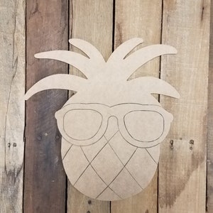 May include: A wooden cutout of a pineapple wearing sunglasses. The pineapple has a detailed design with a textured surface and a leafy crown.