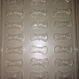 May include: Clear plastic mold with 18 scroll-shaped cavities. Each scroll has a tied ribbon detail. The mold is labeled "LIFE OF THE PARTY" and "08886".