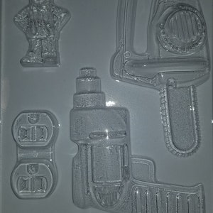 May include: A gray plastic mold with four different shapes: a cartoon construction worker holding a hammer, a chainsaw, a drill, and a power outlet. The mold is labeled "Life of the Party 856".
