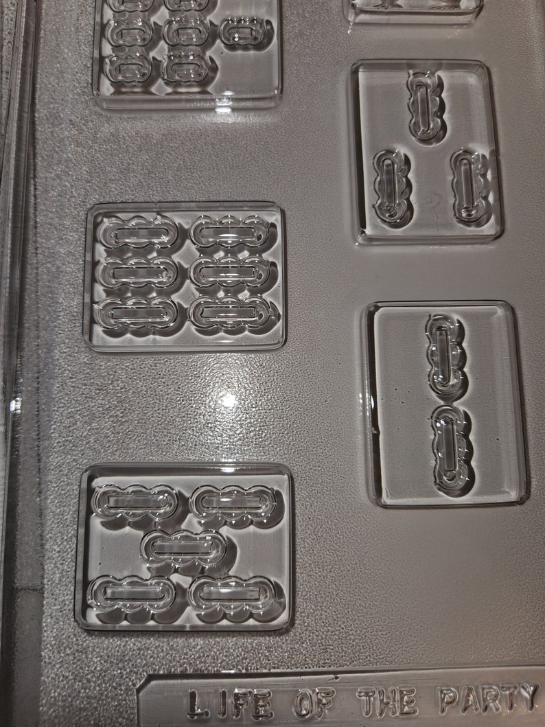 May include: Clear plastic candy mold with various shaped cavities. The mold has rectangular and square sections with cloud-like and oblong shapes. The text "LIFE OF THE PARTY" is embossed at the bottom of the mold.