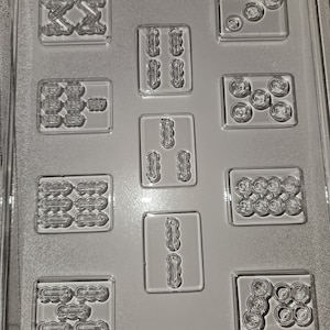 May include: Clear plastic candy mold with various shapes, including circles, zigzags, and oblongs. The mold is divided into rectangular sections, each containing a different design. The text "LIFE OF THE PARTY M 269 - G" is visible at the bottom.