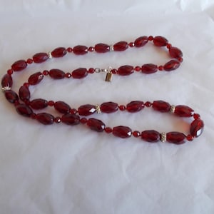 May include: A long, double-strand necklace made of faceted, dark red glass beads with silver accents.