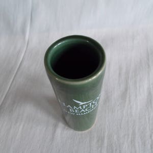 May include: A green ceramic shot glass with white text that reads "Hampton Beach New Hampshire".
