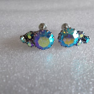 May include: A pair of iridescent blue and green clip-on earrings with a cluster of smaller stones.