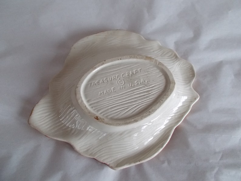 May include: White ceramic serving dish with a scalloped edge. The bottom of the dish has a brown oval label with the text "Treasure Craft Made in U.S.A."
