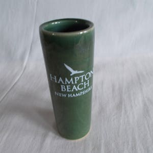 May include: A green ceramic shot glass with a white bird and the text "Hampton Beach New Hampshire".