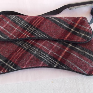 May include: A red, black, and white plaid crossbody bag with a black strap.
