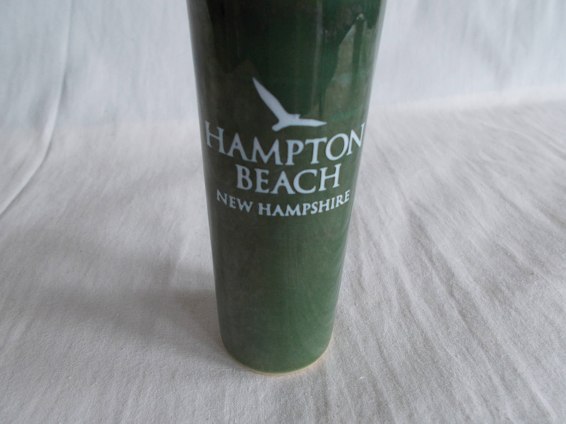 May include: A green ceramic vase with a white silhouette of a bird and the text "Hampton Beach New Hampshire".